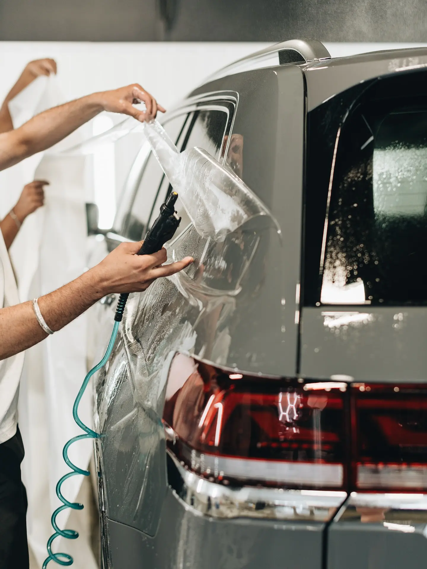 Cobra Auto Styling installers wrapping XPEL film around the rear quarter of a dark SUV
