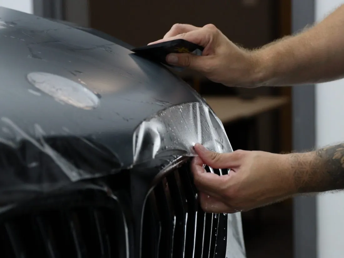 Cobra Auto Styling installer squeegeeing XPEL paint protection film over a front fender in Prince George